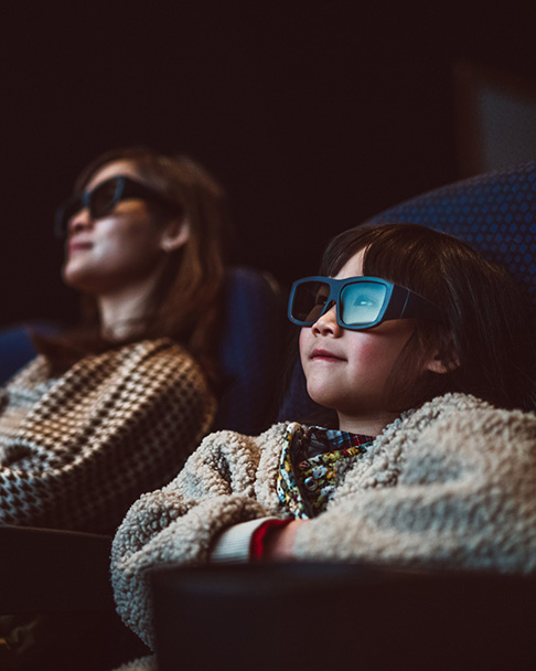 Two people wearing 3D glasses watching a film in a cinema.