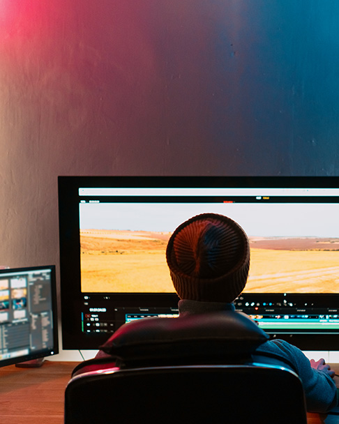 Person reviewing and editing video footage on a large monitor using professional post-production software.