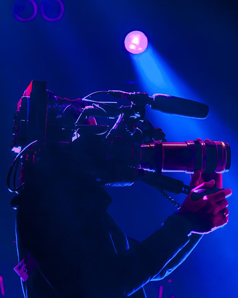 A camera silhouetted against blue and pink studio lighting