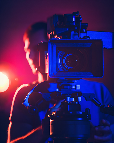 Camera operator using a professional video camera under studio lighting.